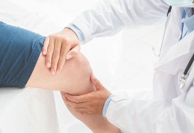理疗师对病人的腿进行康复治疗。运动理疗概念，全景横幅
