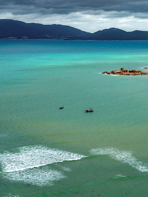 越南，芽庄，海上有渔船。从鸟瞰海岸的景色。碧绿的大海，波浪和山脉在背景中