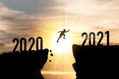 欢迎圣诞快乐和2021年新年快乐，剪影人从2020悬崖跳到2021悬崖，云天和阳光。