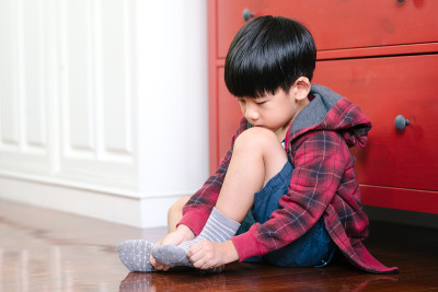 可爱的亚洲男孩穿好衣服去上学，穿上袜子，带着幸福的笑容回到学校