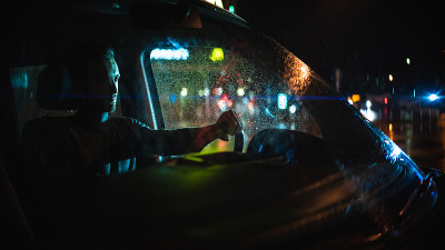 在雨夜的街道上，那个英俊的男人坐在车里