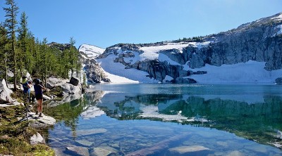 游客在清澈的高山湖泊拍照。
