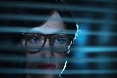 神秘复古的80年代女商人戴着眼镜透过百叶窗看。
