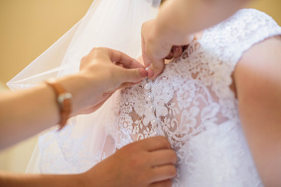 妈妈帮助新娘穿上白色和美丽的婚纱