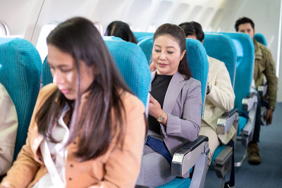 为了安全飞行，女商人坐在飞机上时系好安全带。乘飞机旅行既舒适又安全。安全系统严密。国际航空公司。长途