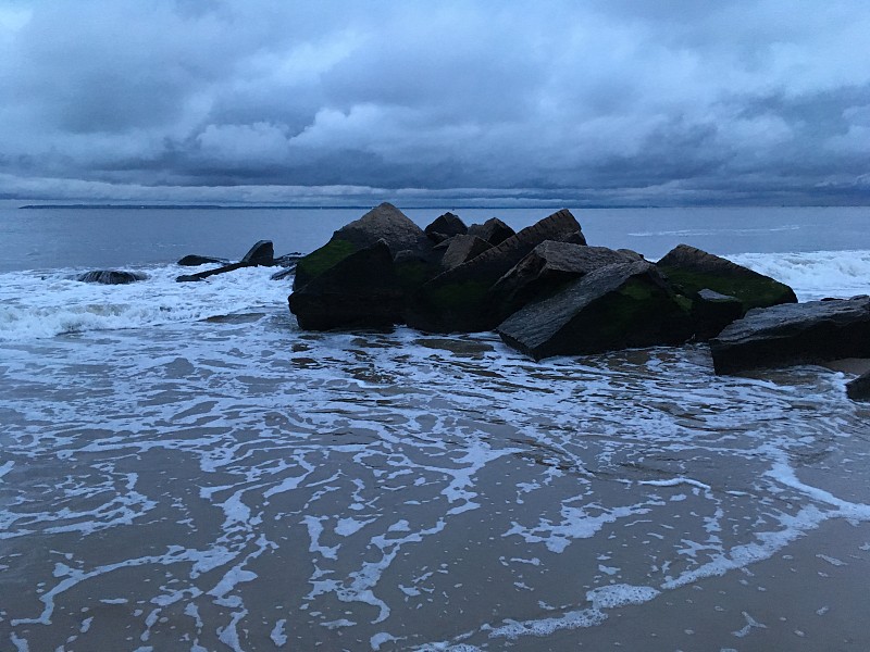 在春天阴天下雨后的康尼岛海滩日落在布鲁克林，纽约，纽约。