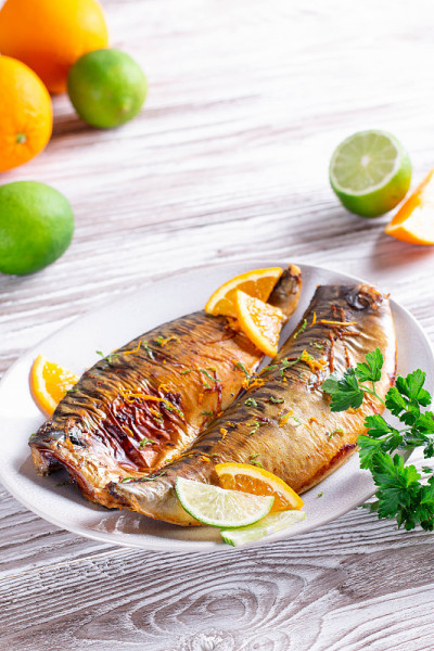 美食:烤鱼、酸橙、橙片和橙汁放在盘子里特写