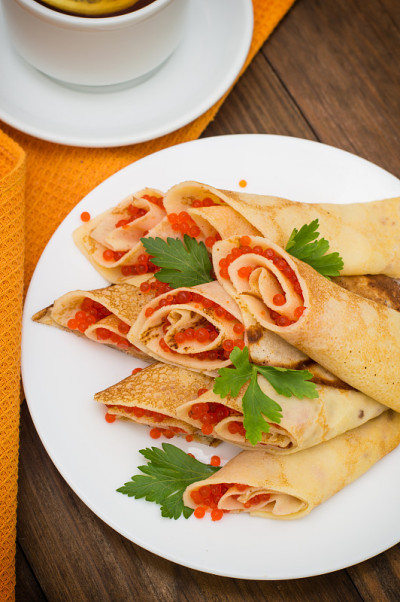 红鱼子酱煎饼卷。俄罗斯菜。平的。Maslenitsa。木制背景。前视图。特写镜头