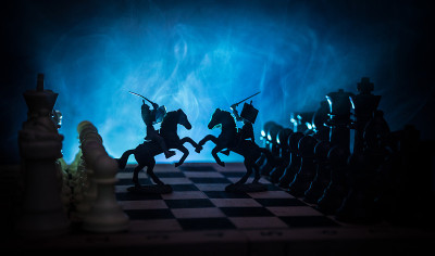 中世纪的战斗场景，骑兵和步兵在棋盘上。棋牌游戏的商业理念和竞争理念与战略理念棋牌人物在黑暗的背景下