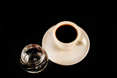 白杯子里的黑咖啡和一杯加咖啡豆的萨姆布卡