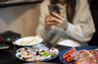 一个女人在餐厅用手机拍食物照片