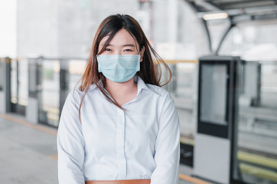 An Asian woman wearing a mask stands in queue wait