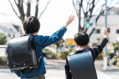 日本小学高年级学生和一年级学生在十字路口举手