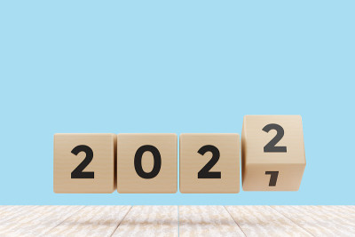 2022年新年快乐。木制立方体，2021号改为2022号，白色桌子，蓝色背景。3 d图呈现。