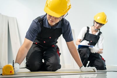 亚洲建筑工人男在走廊上用卷尺量拼花地板。木工建筑女工帮助和支持工匠的工作，修理和安装地板上的强化板，
