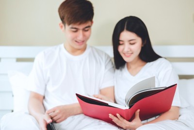 亚洲夫妇看书，买人寿保险，买房子，看结婚照。
