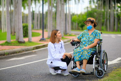 亚洲女医生照顾老年病人如何使用电动轮椅。
