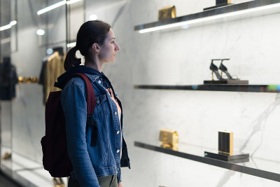 一位妇女站在一家精品商店的橱窗前看鞋。