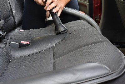 一名男子正在用吸尘器清洁汽车座椅内部