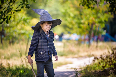 头戴尖顶帽子的小男孩在户外玩魔杖。小向导。万圣节的概念