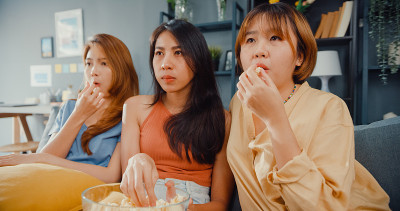有吸引力的亚洲可爱的淑女女孩团体积极的高兴的高兴的与随意有乐趣，享受看在线电影娱乐在客厅的沙发在家里