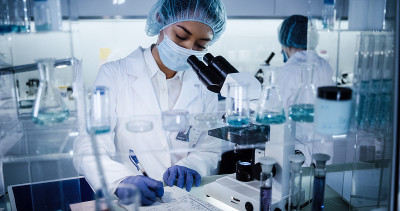 研究DNA突变的多种族女性团队。在防护服中使用显微镜