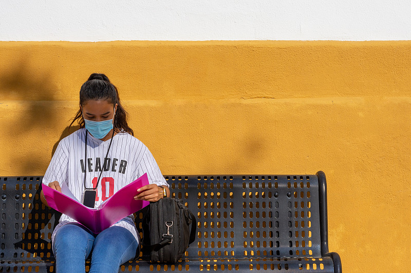 College girl sitting on a bench studying on campus