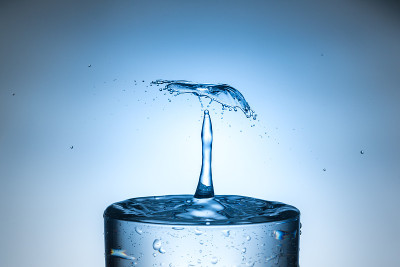 水滴从孤立的明亮背景溅入玻璃。