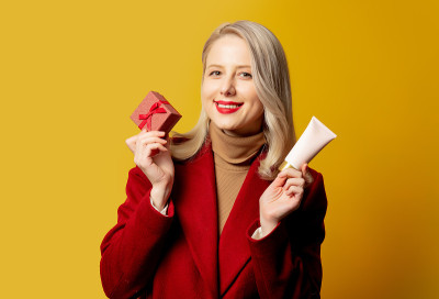 穿着红色外套的漂亮女人，带着礼盒和奶油色软管