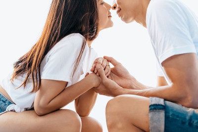 一对情侣坐在沙滩椅上，手牵着手在早上的海滩上。一对新婚夫妇在浪漫的假期
