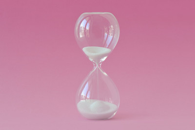 粉色背景上的沙漏——女性健康、生育能力和生物钟的概念