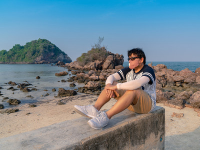 孤独的亚洲男人坐在沙滩上思考