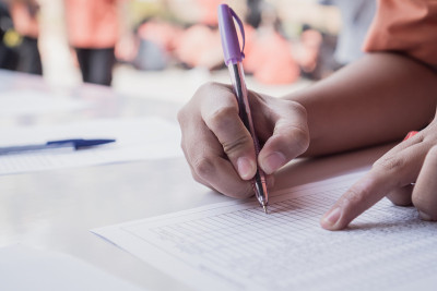 学生拿着笔在纸上签名或笔记在高中活动学习