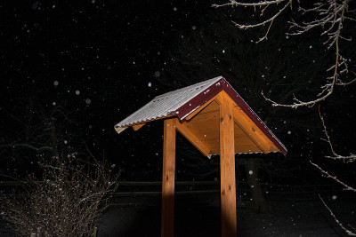 木井上覆盖着第一场雪，背景是村庄的夜晚。