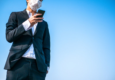 一名戴着面具的商人正在操作智能手机