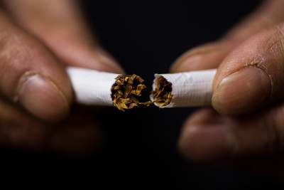 一位中年妇女的手捏碎了一根香烟