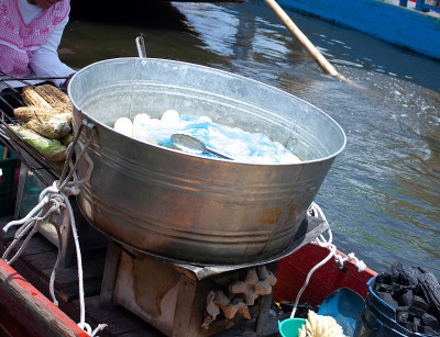 在墨西哥城的主要旅游景点Xochimilco，一名船上的玉米销售者向派对参与者出售