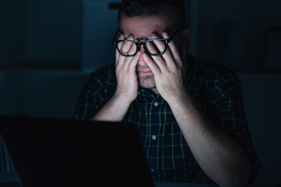 一个疲惫的人在深夜用笔记本电脑工作