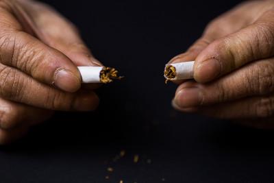 一位中年妇女的手捏碎了一根香烟
