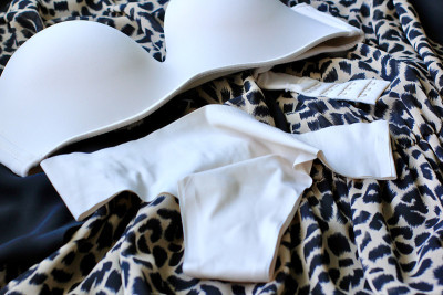 皮肤米色女性内衣:乳罩、内裤和香水躺在动物豹纹衣服的背景上。美丽、时尚的概念。基本的内衣。