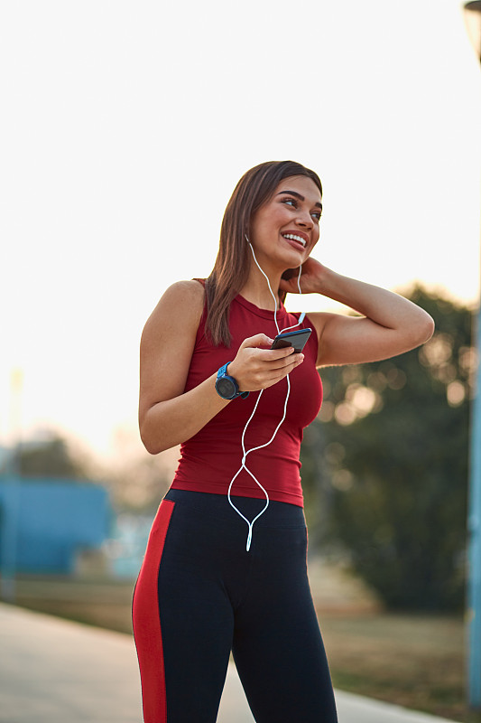 现代年轻女性在慢跑时用手机让自己停下来。