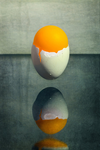 蛋壳和一个橙色的球悬浮在桌子上方，超现实的静物画“早晨”