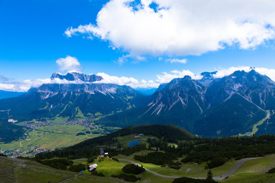格鲁比格斯坦的全景无人机视图，崎岖的Zugspitze在蓝色晴朗的天空和积云的背景下。在蒂罗尔的勒莫