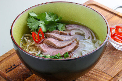 亚洲辣汤配小牛肉放在木板上。在白色背景上。