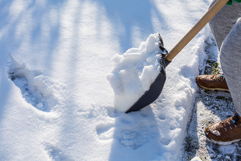 郊区的孩子在他的房子前铲雪