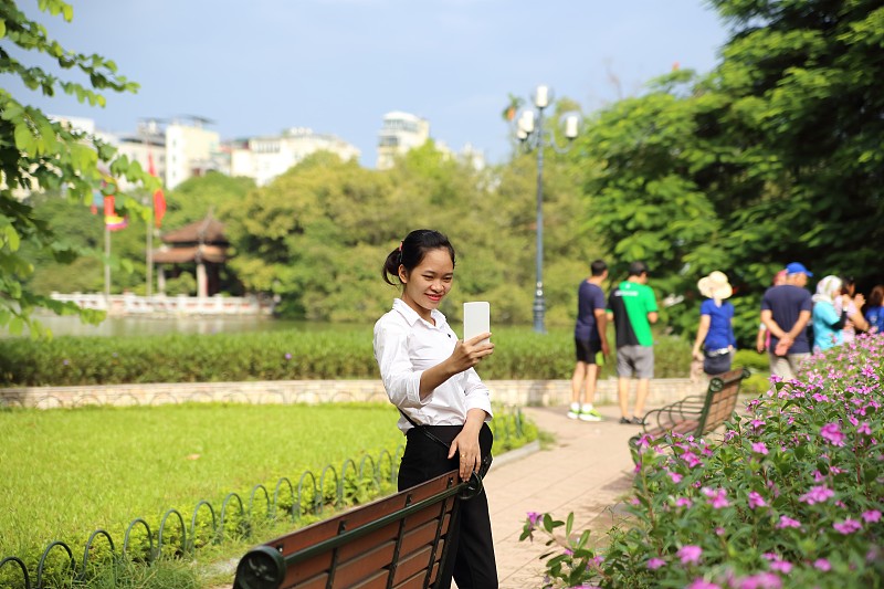 一名年轻女子在河内用智能手机拍照