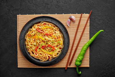 辣椒蒜味客家面在黑色的碗里，在黑色的石板桌上。印中素食菜肴。印度蔬菜面条。典型的亚洲餐。俯视图