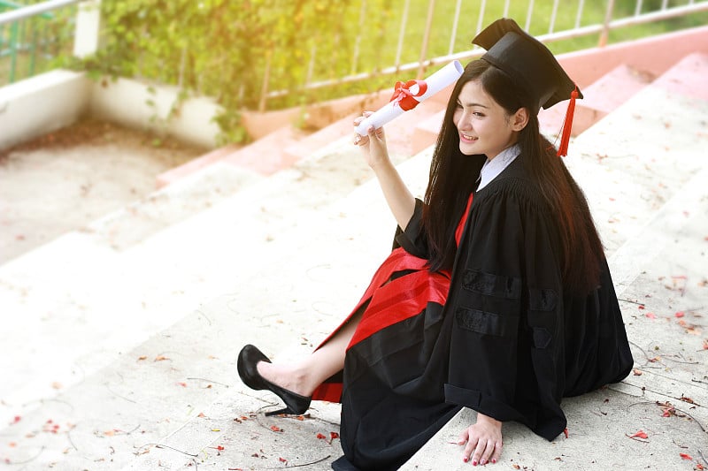 毕业的学生戴着黑色的帽子，手拿证书在体育大学完成学业，概念毕业日