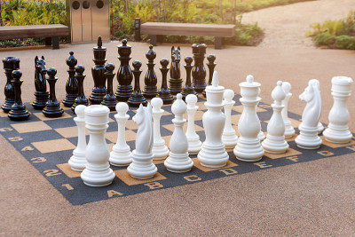 带有大塑料棋子的户外棋盘。大型象棋在公共区域区域。近距离观察公园里街头象棋的大棋子和巨大棋盘