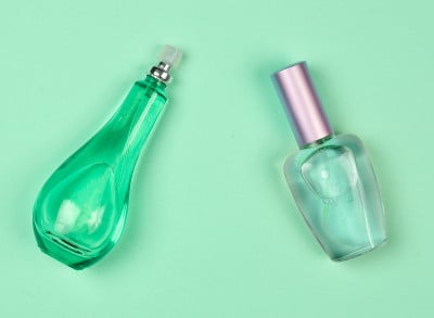 蓝色粉彩背景上的两瓶女性香水。前视图。女性化妆品及配饰。